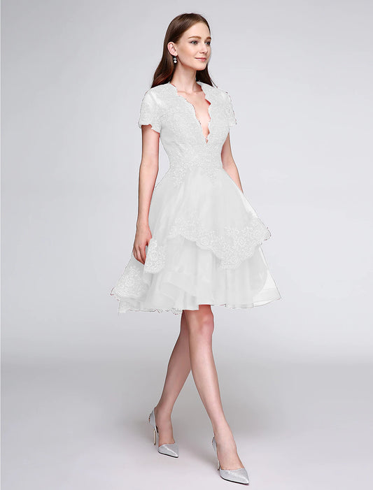 Elegant knee-length organza cocktail dress featuring a plunging neckline and short sleeves.