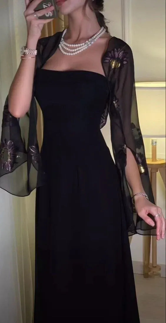Close-up of black strapless gown and sheer bell-sleeve shrug with purple-gold floral embroidery.