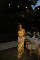 Elegant golden-yellow mermaid prom dress with cowl neck, spaghetti straps, and high slit.