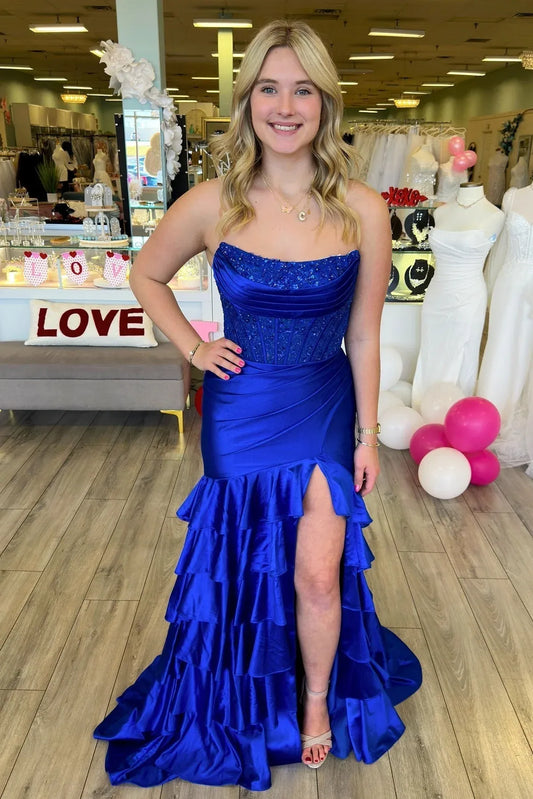 Elegant royal blue strapless mermaid prom gown with beaded corset and ruffled high-slit skirt.