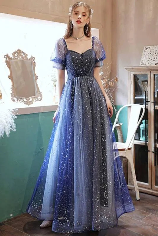 Model wearing a blue gradient glitter A-line prom dress with puff sleeves and a sweetheart neckline.