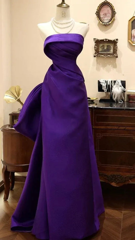 Model wearing a regal royal purple mermaid prom dress with a strapless draped bodice.