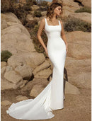 Model wearing a white beach mermaid wedding dress with square neck and open back, showing court train.