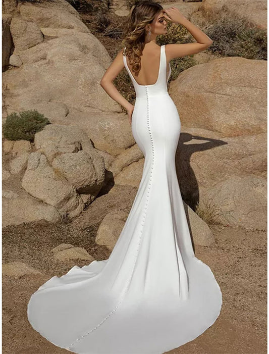 Close-up of the open back and button details on a white mermaid wedding dress.