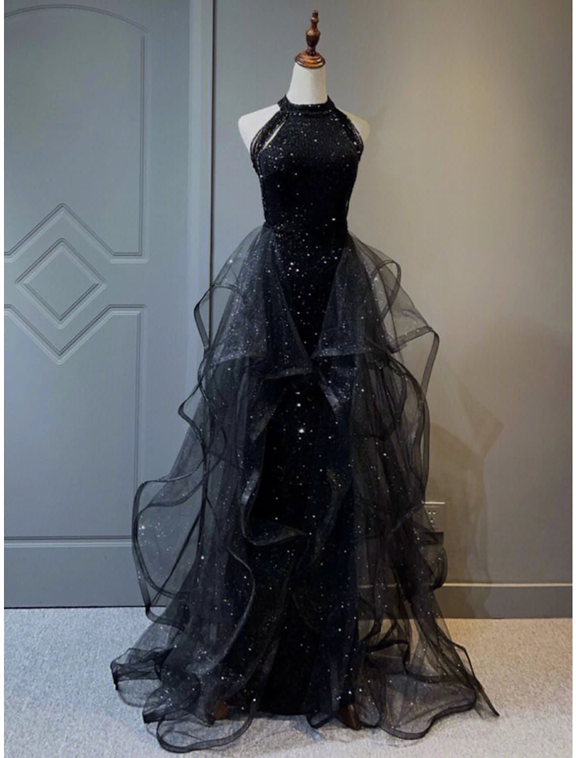 Woman wearing a dazzling A-line halter sequined prom dress with a sweep train.