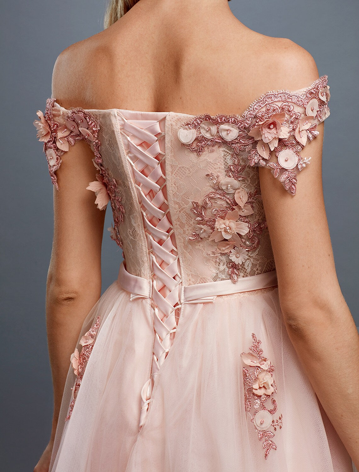 Close-up of the floral appliques and off-shoulder neckline on the tulle wedding guest dress.