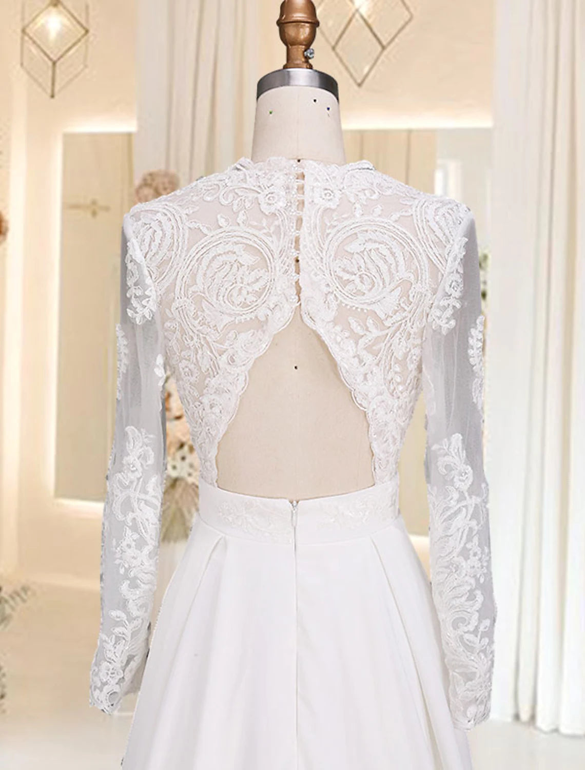 Close-up of V-neck bodice, long sleeves, and appliques on satin wedding dress.